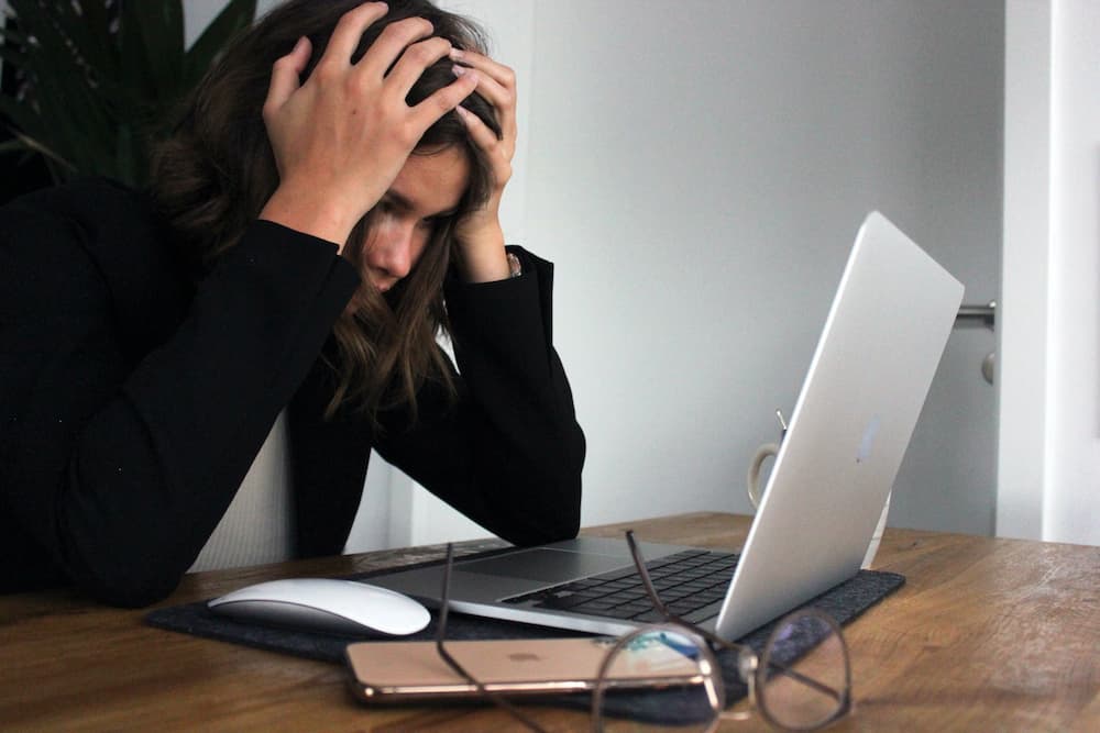 stressed woman with her hands on head looking at her laptop